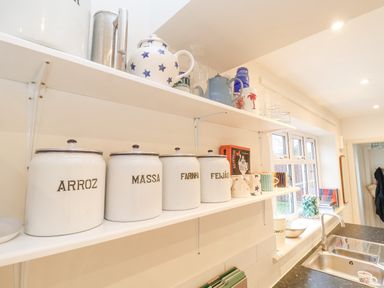 A kitchen shelf with labeled jars cups and teapots above a sink at 3 Chantry Cottages Campsea Ashe near Woodbridge