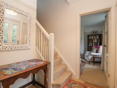 A hallway with carpeted stairs a wooden table with a puzzle and a mirror on the wall at 3 Chantry Cottages in Campsea Ashe near Woodbridge