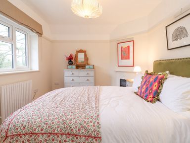 A bedroom with a bed a chest of drawers with a mirror and a window at 3 Chantry Cottages Campsea Ashe near Woodbridge