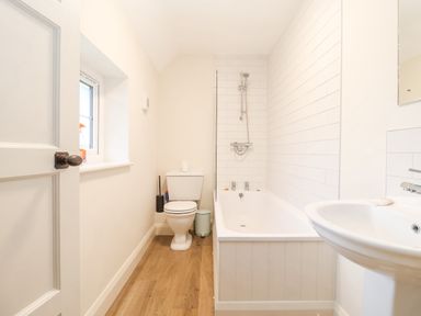 A bathroom with a toilet sink bathtub with shower and a window at 3 Chantry Cottages in Campsea Ashe near Woodbridge