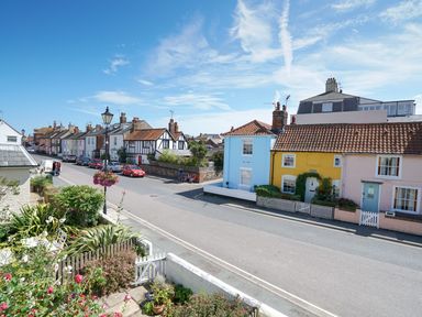 A street view with colorful houses cars and plants at The Corner Cottage in Aldeburgh