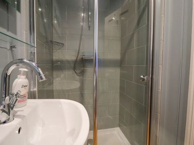 A bathroom with a sink and a shower with glass doors at The Corner Cottage in Aldeburgh