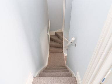 A narrow carpeted staircase with handrails on both sides at The Corner Cottage in Aldeburgh