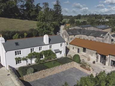 An outdoor view of a house and farm buildings at Lower Well Farm House in Totnes