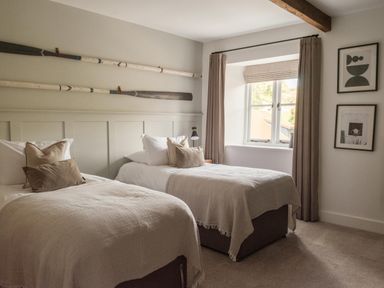 A bedroom with two beds and rowing oars on the wall at Lower Well Farm House in Totnes