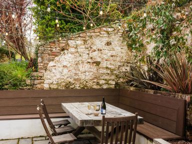 An outdoor seating area with a table and chairs at Lower Well Farm House in Totnes