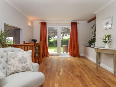 A room with wooden floor and red curtains on glass door leading outside at Hole Park in Holsworthy