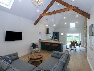 A living room with a sofa and kitchen area at Beudy