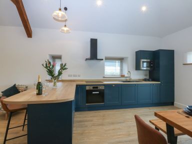 A kitchen with a counter and bar stools at Beudy