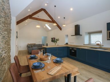 A kitchen with a dining table and chairs at Beudy