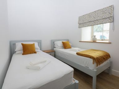 A bedroom with two beds and a window at Beudy