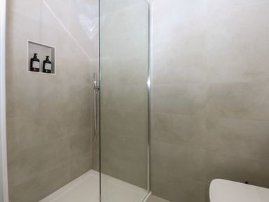 A shower with a glass screen and shelves at Beudy 