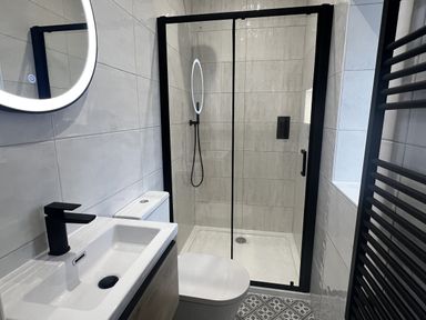 A bathroom with a shower, sink, toilet, and mirror at Beudy Tanrallt in Llanfachraeth
