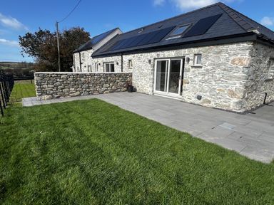 An outdoor area with a stone wall and patio at Beudy Tanrallt in Llanfachraeth