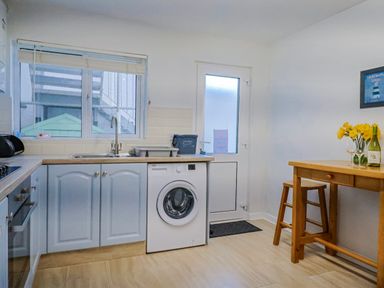 A kitchen with a washing machine and table at Sea Lovers in Exmouth