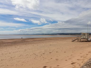 A beach with a lifeguard station and a person walking at Sea Lovers in Exmouth