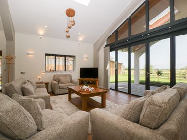 A living room with sofas a wooden coffee table a tv and large glass doors overlooking a garden at Hidden Well in Aust