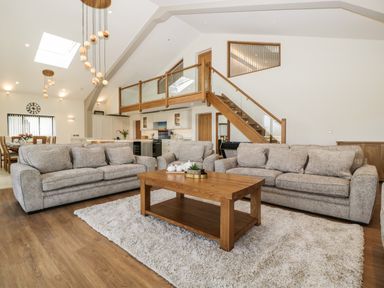 A living room with two sofas a coffee table a rug a staircase and a dining area at Hidden Well in Aust