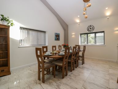 A dining room with a wooden table and chairs set with dishes and glasses at Hidden Well in Aust