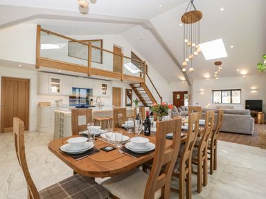 An open plan kitchen dining and living area with wooden furniture and glass railing at Hidden Well in Aust