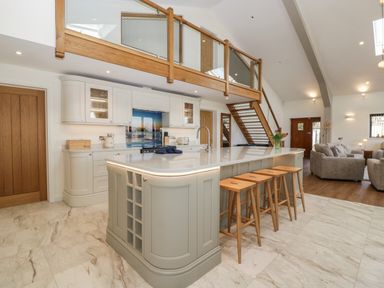 A kitchen with a large island with stools and a living area with sofas at Hidden Well in Aust