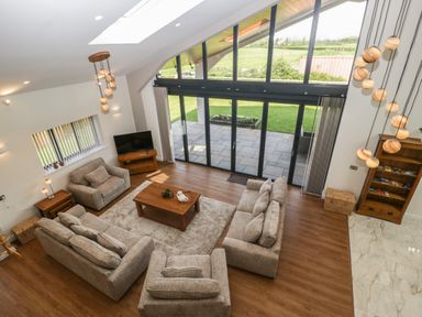 A living room with sofas a coffee table a television and large glass doors opening to a patio at Hidden Well in Aust