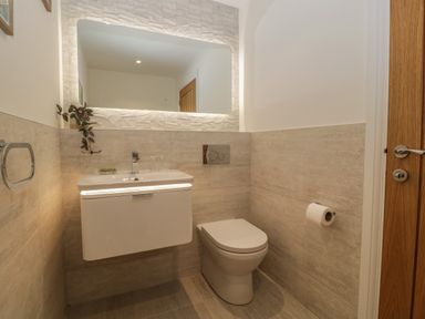 A bathroom with a toilet a washbasin with a mirror above and a wooden door at Hidden Well in Aust