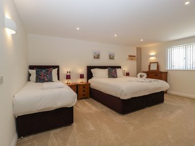 A bedroom with a double bed and a single bed wooden bedside tables and lamps at Hidden Well in Aust