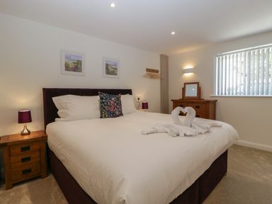 A bedroom with a double bed bedside tables lamps and a wooden dresser with a mirror at Hidden Well in Aust