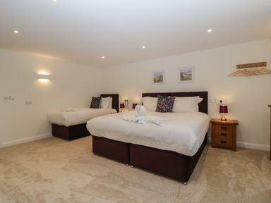 A bedroom with two beds a bedside table with a lamp and wall paintings at Hidden Well in Aust