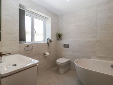 A bathroom with a sink vanity a toilet and a bathtub near a window at Hidden Well in Aust