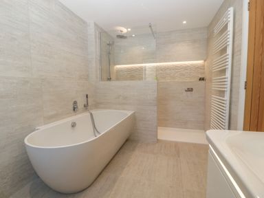 A bathroom with a freestanding bathtub a walk-in shower and a heated towel rail at Hidden Well in Aust
