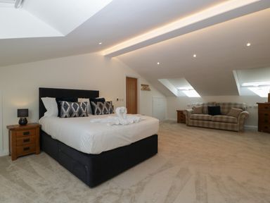 A bedroom with a bed and a sofa under slanted windows at Hidden Well in Aust