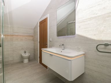A bathroom with a wall-mounted sink cabinet mirror wooden door and bidet at Hidden Well in Aust