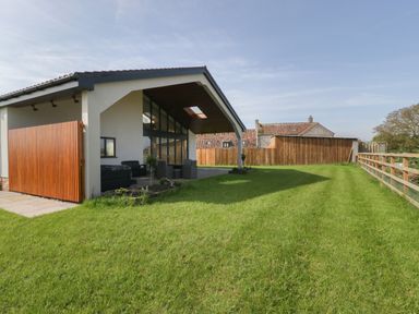 A backyard with green grass a covered patio area with outdoor furniture and wooden fencing at Hidden Well in Aust