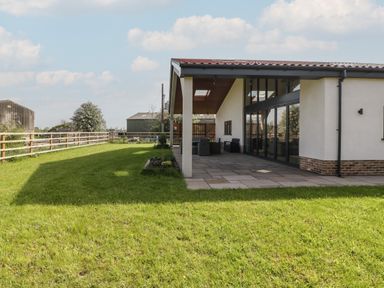 A covered patio area with outdoor furniture next to a lawn and fenced yard at Hidden Well in Aust