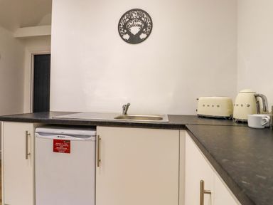 A kitchen countertop with a sink a toaster a kettle and a small refrigerator underneath at Kingfisher Cottage in Ottinge near Lyminge