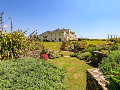 A garden with bushes flowers and benches leading to a residential building at 5 Thurlestone Beach in Thurlestone