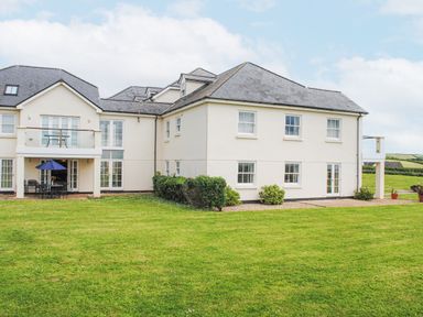 A building with multiple windows and balconies facing a large green lawn at 5 Thurlestone Beach in Thurlestone