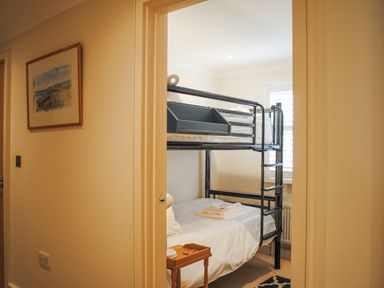 A bedroom with black metal bunk beds a small wooden side table and a framed picture on the wall at 5 Thurlestone Beach in Thurlestone