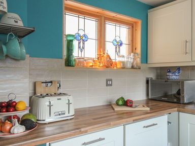 A kitchen countertop with a toaster fruit and vegetables jars and a microwave at Cove Cottage Hideaway in Chiswell On Portland