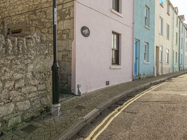 A street with pastel colored cottages and a black lamp post at Cove Cottage Hideaway in Chiswell On Portland