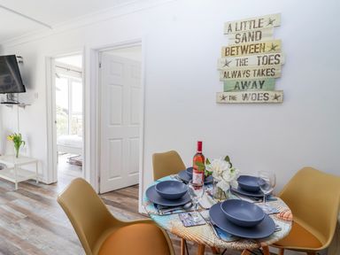 A dining room with a table set for a meal at Shells Cottage in Looe