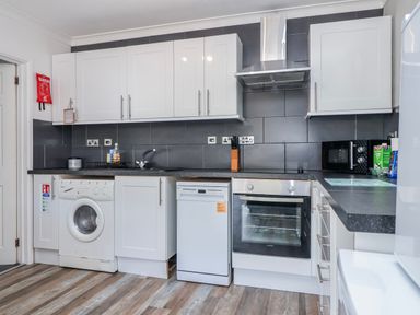 A kitchen with appliances including a washing machine and dishwasher at Shells Cottage in Looe