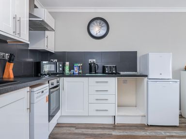 A kitchen with cabinets, oven, sink, fridge, and microwave at Shells Cottage in Looe