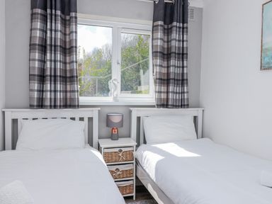 A bedroom with twin beds and a lamp at Shells Cottage in Looe