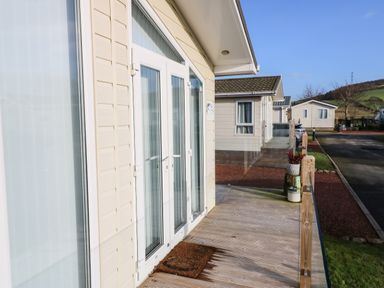 A porch with a doormat and flower pots outside light-colored houses at A and C Lodge-Plot 21 in Armathwaite