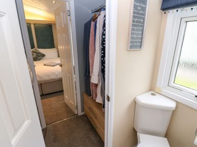 A bathroom with a toilet and a view of a bedroom at A and C Lodge-Plot 21 Armathwaite