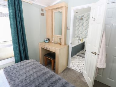 A bedroom with a vanity desk and bathroom door at A and C Lodge-Plot 21 Armathwaite