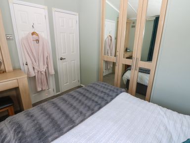 A bedroom with a bed, wardrobe, and robe hanging at A and C Lodge-Plot 21 Armathwaite